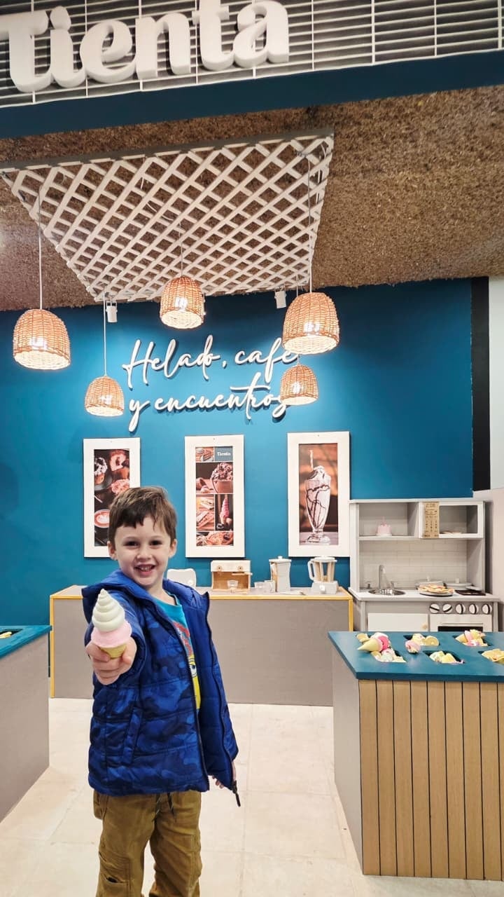 Chico sosteniendo un helado de Tienta bajo el cartel Helado, café y encuentro